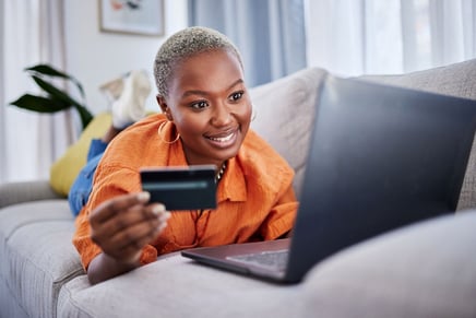 consumer laying on a bed using a credit card to shop online through an ecommerce loyalty program