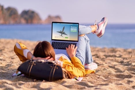 employee laying on the beach booking more travel from company