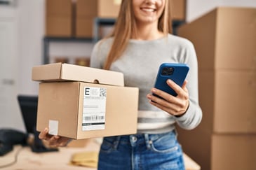 woman holding packages and a phone for her ecommerce business, calculating LVT and CAC